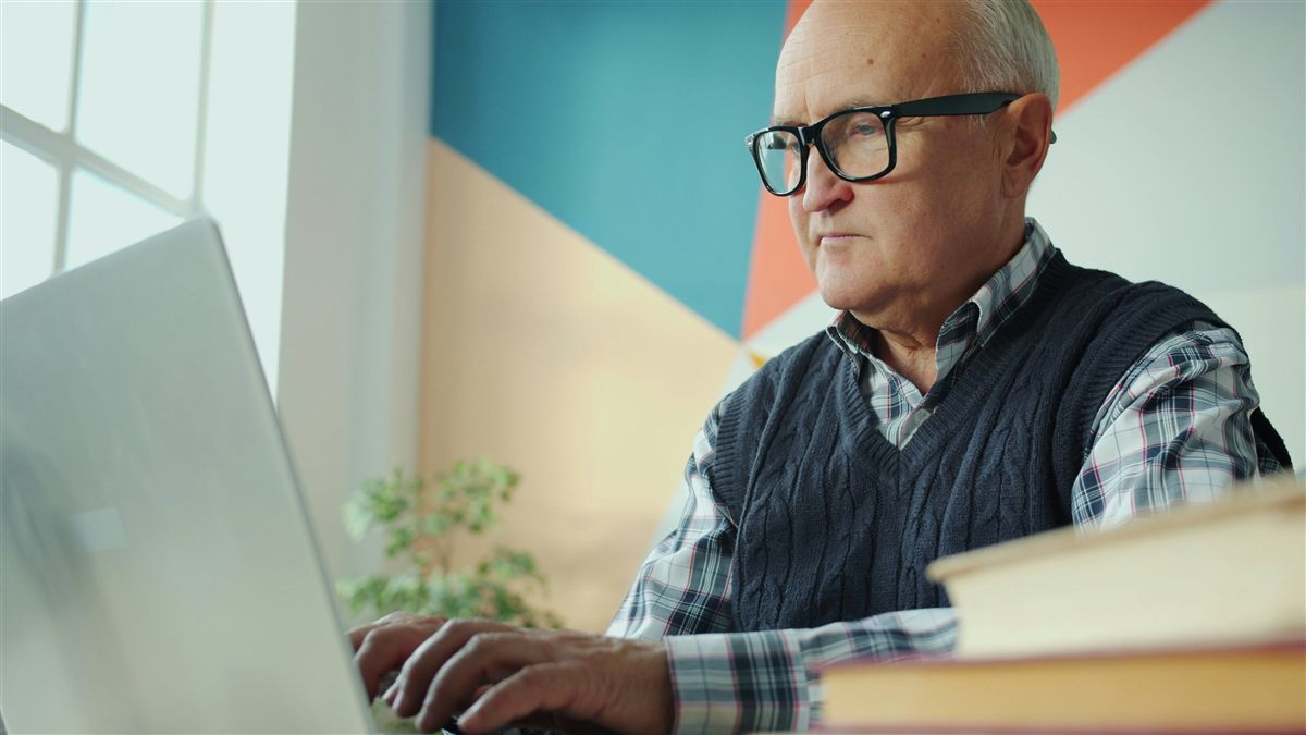 Personne senior apprenant à utiliser un ordinateur portable avec l’aide d’un accompagnant