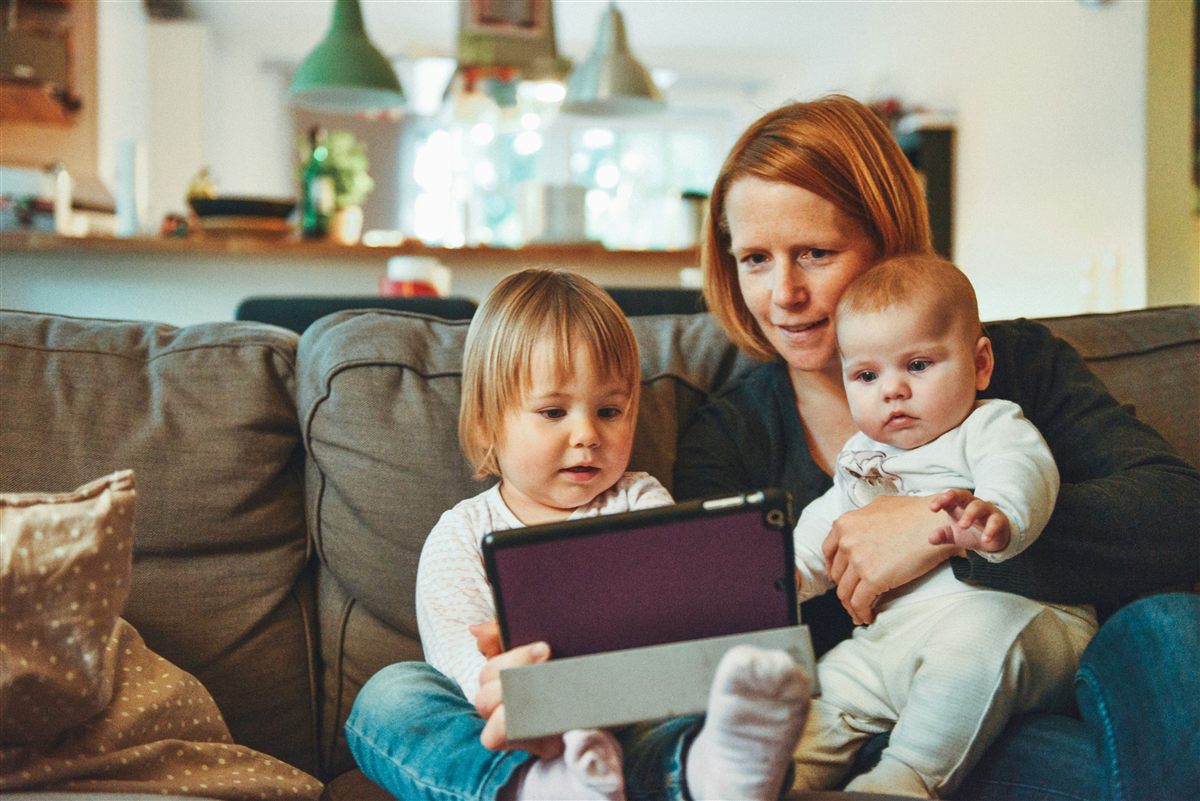 Enfant utilisant une tablette à la maison sous le regard attentif d’un parent